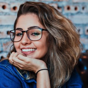 A girl in glasses smiling with invisalign