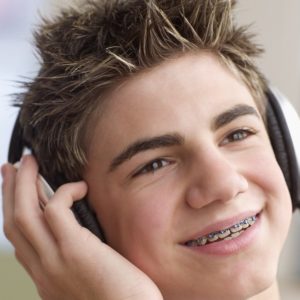 a male teenager in braces listening to music